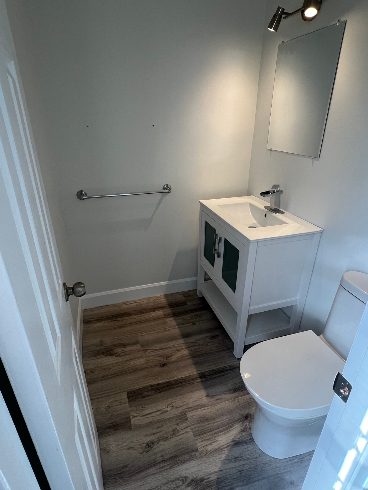 A powder room refreshed by R&H with a new vanity, toilet, lighting and mirror